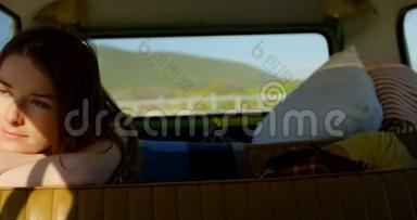 一位体贴的美丽的年轻女子坐在面包车里，一边看着一边